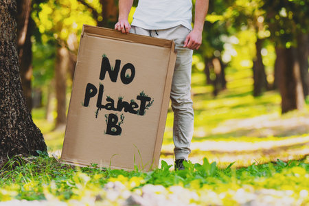 Cropped photo of an activist man with banner No Planet B protesting over pollution and global...