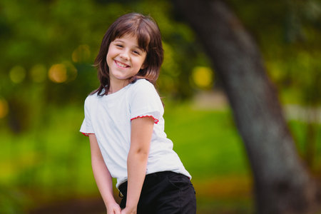 Close up photo of a happy smiling young girl in black and white clothes feeling carefree being outdoors tilting her head to the side of the shoulder.の写真素材