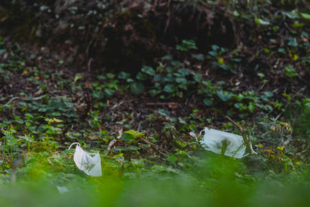 Close up picture of two medical masks thrown to the ground in the park after using them by people, concept of global pollution.の写真素材