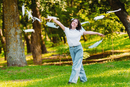 Close up photo of a happy young woman activist being outdoors throwing the medical masks and...