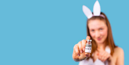 Close up view of a young lady wearing the hoop with hare ears on her head and showing the bottle of vaccine.の写真素材