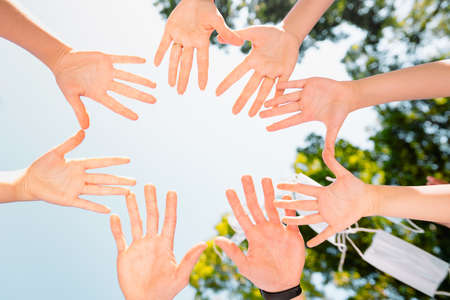 Close up photo from above of different people palms showing unity and support after throwing all medical masks in the air, feel freedom.の写真素材
