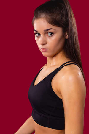 Close-up of beautiful brown-eyed brunette sporty girl with long ponytail in top sports wearing looking at the camera intently.の写真素材
