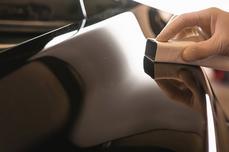 Car polish wax worker hand in protective gloves holds a polisher in the hand and polishes the car with nano ceramic, tools for polishing.の写真素材
