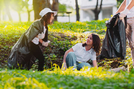 Volunteer charity environment, eco-friendly volunteers holding packets and gathering garbage outdoors and having fun while working.の写真素材