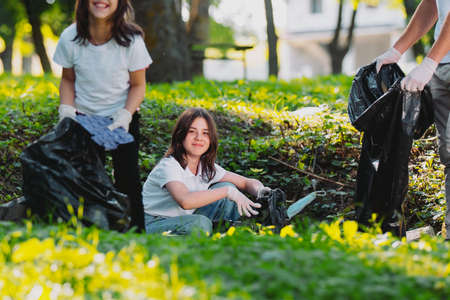 Volunteer teenagers and a man participate in mission for making planet cleaner and in save, gathering the garbage outdoors, voluntary work.の写真素材
