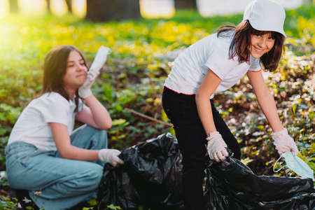 Close up photo of two volunteer girls happy participate in voluntary mission for cleaning nature from the garbage.の写真素材