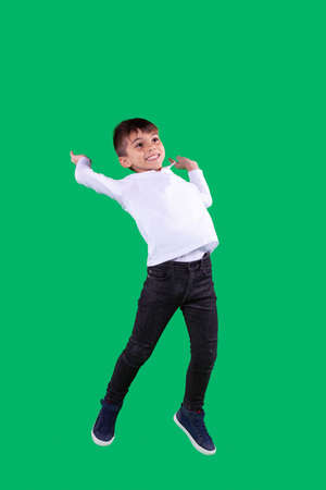 Full-length photo of a school boy wearing school uniform having joyful mood jumping up with facial expression and looking up.の写真素材
