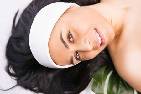 Portrait of a beautiful woman with black hair wearing white bandage on her head looking at the camera in the beauty salon.の写真素材