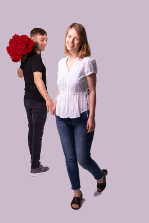 Full-length photo of two pretty people, courier man holding the beautiful bouquet of flowers and lookin at the woman, she is smiling and touches his hand.の写真素材