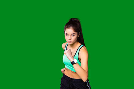 The front view photo of a serious sporty girl wearing the turquoise top and black shorts with white stripes making fitness exercises to keep her body in good shape.の写真素材