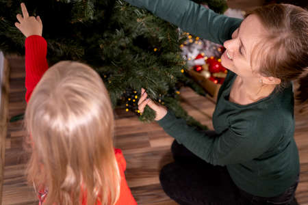 Tradition to decorated Christmas tree, mother and daughter start to decorate Christmas tree together with colored bubbles.の写真素材