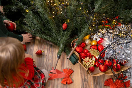 Photo from above of a little girl with her mother on the floor among tree details and decorative toys for Christmas tree.の写真素材