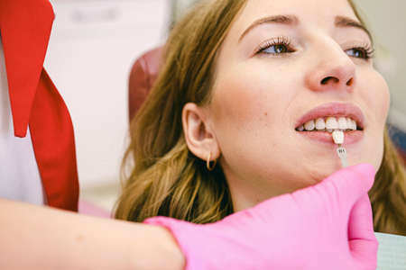 Close up photo of a patient woman and professional stomatologist holding dental crown for female patient in dental clinic.の写真素材