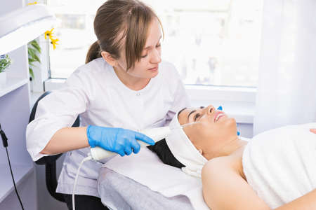 Cosmetologist makes procedure microdermabrasion on the face against acne to a woman, rejuvenation cosmetology concept.の写真素材