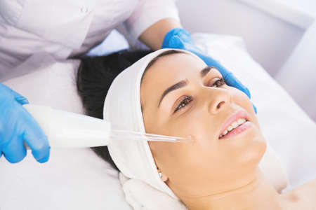 Close up photo of a happy woman receiving rejuvenation cosmetology procedure non injection mesotherapy.の写真素材