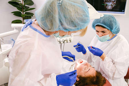 Dentists are working in modern stomatology clinic using instruments to help the patient to have healthy teeth and smile.の写真素材