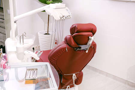 Photo of a stomatology cabinet with a chair, dentist instruments on the table for work and a flowerpot.の写真素材