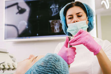 Close up photo of a medic dentist in uniform preparing dental equipment to begin to work with a patient in her office clinic.の写真素材