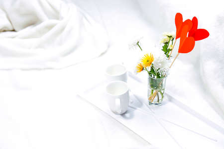 Romantic breakfast in white bed with vase of flowers and two cups for young couple, relax time in honey moon.の写真素材