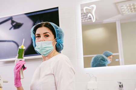 Close up photo of a dentist woman in medical uniform holding in her hand dental filling gun in her medical clinic.の写真素材
