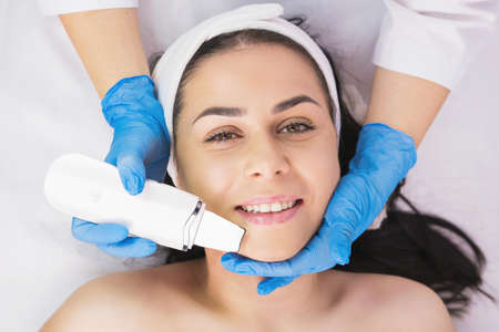 Anti acne surgery cleaning woman face by a cosmetologist in blue gloves using ultrasonic skin equipment, rejuvenation skincare beauty concept.の写真素材