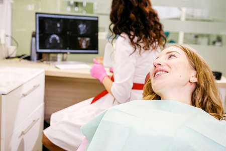 Beautiful young woman patient smiling for the doctor dentist while she looking at the teeth snapshot on the computer.の写真素材