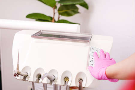Stomatological instrument in the dentists clinic, hand in pink glove pushing at the button on dental high speed turbine.の写真素材