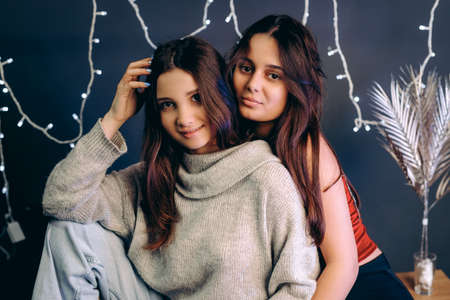 Close up photo of two girls beautiful friends posing for the camera over grey background and illumination.の写真素材