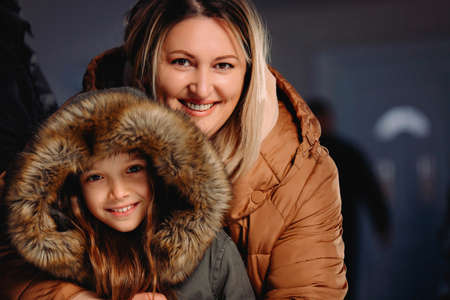 Close up photo of joyful mother and lovely daughter wearing winter clothes outside posing on new year eve.の写真素材