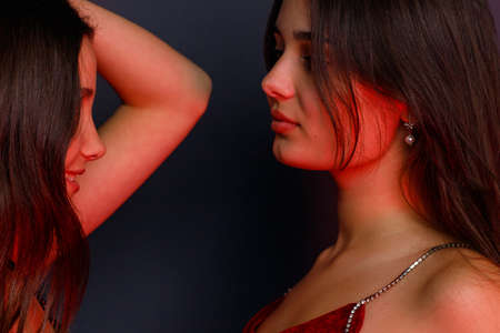 Side view photo of two exited young women wearing evening clothes for the party looking at each other over grey background.の写真素材