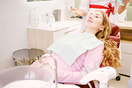 Beautiful young woman doing tooth examination in the dental office on a dental chair in dentistry, health teeth concept.の写真素材