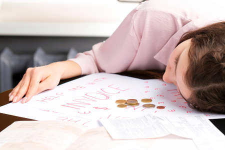 Young tired and desperate business woman suffering stress about accounting debt bills, bank papers, expenses and payments.の写真素材