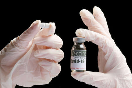 Doctor hands in white gloves holding remedy tablet and a vial of vaccine on pandemic time for the people health.の写真素材