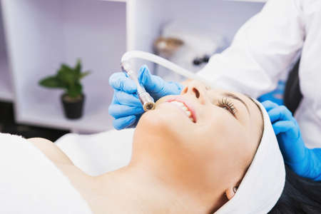 Cosmetologist makes procedure microdermabrasion against acne and blackheads to a woman in the beauty salon.の写真素材