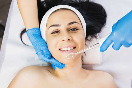Top view photo of a joyful woman face lying on a massage table and getting rejuvenation procedure with a vacuum massage instrument.の写真素材