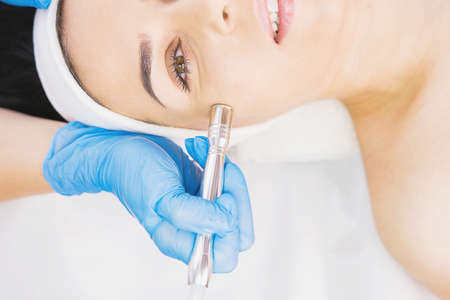 Cropped photo of a young woman passing face vacuum cleaning in a clinical beauty salon by a cosmetologist.の写真素材