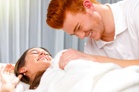 A young red hair man woke up his girlfriend and they are smiling together, loving couple on honey moon.の写真素材