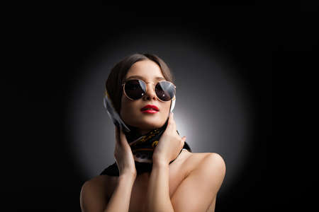 Close up photo of an attractive young woman with bare shoulders in sunglasses and beautiful shawl with make-up, retro music concept.の写真素材