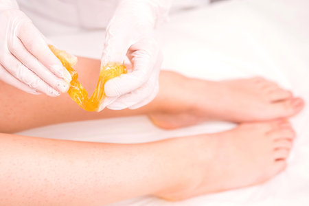 Close up photo of woman legs getting sugar past procedure to remove hair from her legs, body care,...