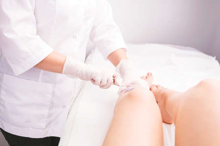 Cosmetician applies sugar pasta , hot wax on woman female leg in the beauty salon to make hair removal procedure for soft and beautiful leg skin.の写真素材