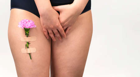 Photo of woman body intimate part in black lingerie covering intimate part with her hands on white background.の写真素材