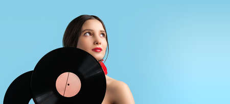 Attractive sensual young woman with red color lips looking up holding two music records retro in her hands over turquose background, copy space.の写真素材