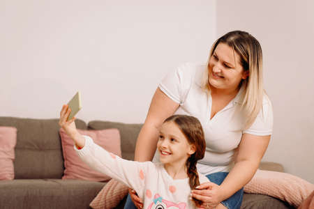 Mother and little dayghter have fun posing for self-portrait picture together enjoy playful weekend at home.の写真素材