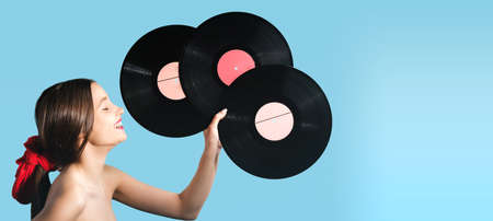 Cute happy girl holding in her hand three music records black color feeling good and relaxed, loves music.の写真素材