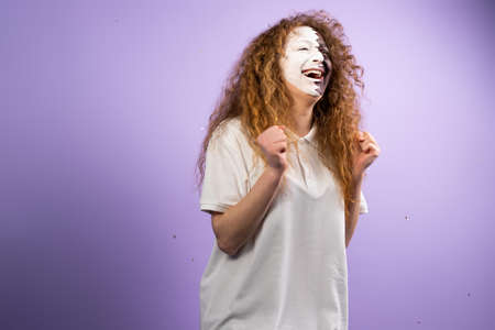 Picture of redhead lady with face painted in Qatar flag raises hands fists wants her favourite football team win the match.の写真素材