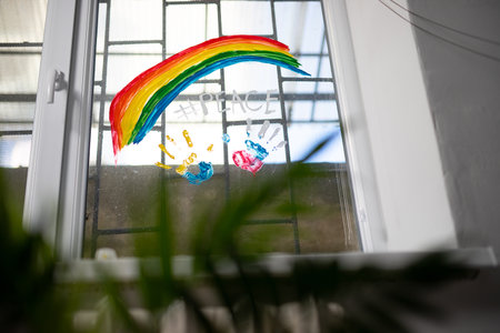 Hand prints of two countries Russia and Ukraine on a window with bars and rainbow sign with word peace, friendship without war concept.の写真素材