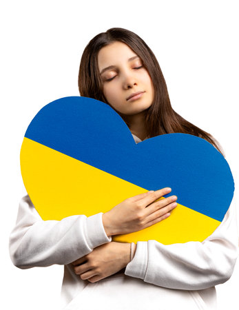 The Caucasian girl has a heart painted with the Ukrainian flag. The concept of peace and well-being isolated on a white backgroundの写真素材