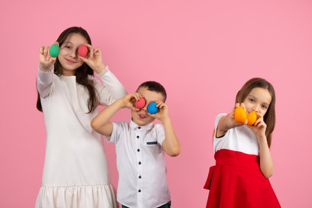 Picture of three children preparing for the Easter holiday holding painted eggs in hands and a boy covering his eyes with eggs, making fun together.の写真素材
