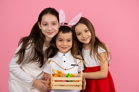 Picture of adorable three children of the family, little boy wearing bunny ears and holding basket of painted eggs.の写真素材